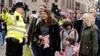 A policeman directs a family to the public viewing areas to watch Britain's King Charles III's procession to Westminster Abbey for his coronation in London Saturday,