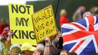 People hold placards on the day of Britain's King Charles' coronation ceremony, at The Mall in London