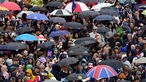 Well-wishers shelter from the rain under umbrellas as they line the route of the 'King's Procession'