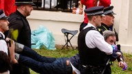 Police officers detain a member of "Just Stop Oil" movement during a protest ahead of Britain's King Charles' procession to his coronation ceremony from Buckingham Palace to Westminster Abbey