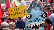 Ein Teilnehmer der Kundgebung zum Tag der Arbeit des Deutschen Gewerkschaftsbundes (DGB) auf dem Kölner Heumarkt hat sich als Hai verkleidet und trägt ein Schild mit der Aufschrift: ·Nicht füttern·.