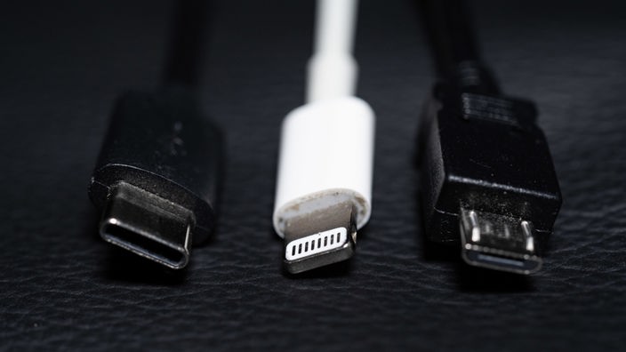 Ein USB-C (l-r), ein Apple Lightning und ein Micro-USB Kabel (l-r) sind nebeneinander zu sehen.