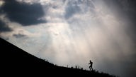 20.07.2022, Nordrhein-Westfalen, Gelsenkirchen: Ein Läufer ist auf der Halde Rheinelbe vor aufziehenden Wolken unterwegs.
