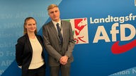 AfD-Jugendlandtags-Abgeordnete Mia und Niklas vor einer AfD-Plagaktwand im Landtag von Nordrhein-Werstfalen