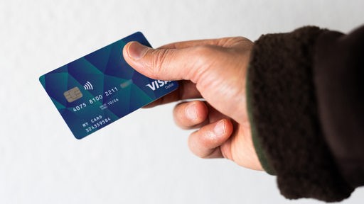 Ein Geflüchteter hält eine Debitkarte in der Hand