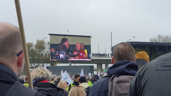 Großer Monitor zeigt das Geschehen auf der Bühne: Die DGB-NRW-Vorsitzende Anja Weber wird von Moderator Christian Hermanns befragt