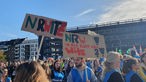 Menschen mit bunten Plakaten demonstrieren vor dem Landtag in Düsseldorf, auf einem steht: "NRW - ist das hier ein Witz!?!"