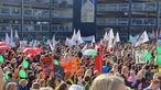 Menschen halten bunte Plakate bei einer Demonstration vor dem Düsseldorfer Landtag