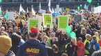 Menschen halten bunte Plakate bei einer Demonstration vor dem Düsseldorfer Landtag