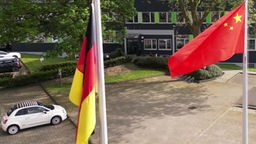 Eine deutsche und eine chinesische Fahne wehen vor einem Bürogebäude
