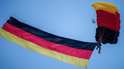Fallschirmspringer der Bundespolizei mit Deutschlandfahne über dem Staatsakt zu «75 Jahre Grundgesetz»