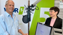 Josefine Paul im steht mit Michael Brocker im WDR 5 Studio und gibt ein Interview. Beide lächeln.