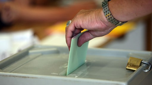 Eine Frau wirft ihren Stimmzettel in die Wahlurne. 
