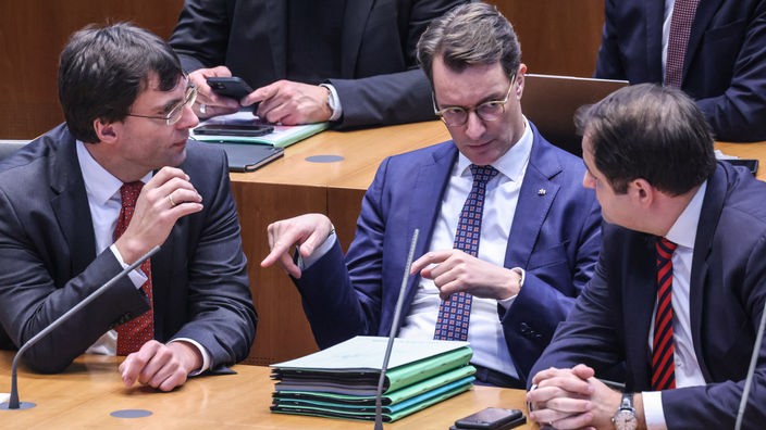 Ministerpräsident Hendrik Wüst spricht im Landtag mit Finanzminister Marcus Optendrenk und Nathanael Liminski, Minister für Bundes- und Europaangelegenheiten