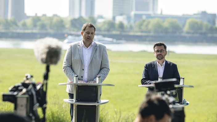 Lars Klingbeil (links) und Thomas Kutschaty stehen am Rheinufer auf einem Podium