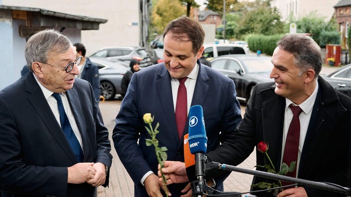 Durmus Aksoy, Vorsitzender des Ditib (Landesverband Nordrhein-Westfalen), überreicht Abraham Lehrer, vor der Sultan Ahmet Moschee eine gelbe Rose. Nathanael Liminski steht zwischen ihnen.
