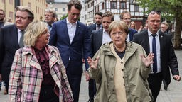 Die ehemalige Bundeskanzlerin Angela Merkel (2.v.r.,CDU) und Hendrik Wüst (M, CDU), Ministerpräsident Nordrhein-Westfalen gehen mit der Bürgermeisterin Sabine Preiser-Marian (vorne links, CDU) durch Bad Münstereifel.
