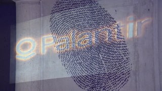 Fingerabdruck mit Beamer an die Wand geworfen, Schriftzug Palantir davor