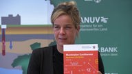 Eine blonde Frau hält eine Broschüre in die Kamera: Mona Neubaur präsentiert den Masterplan Geothermie