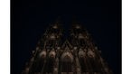 Das Eingangsportal des Kölner Doms in der Nacht, nur schwach vom Licht einiger Straßenlaternen beleuchtet