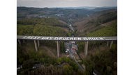 Luftaufnahme zeigt die für den Verkehr gesperrte Rahmedetalbrücke bei Lüdenscheid, auf der Brücke steht in großer weißer Schrift: "LASST UNS BRÜCKEN BAUEN". 