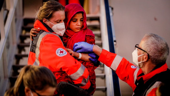 Eine Rot-Kreuz-Helferin trägt ein Mädchen aus Afghanistan auf dem Arm, das am Düsseldorfer Flughafen ankommt. 