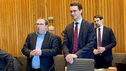 Oliver Krischer (links) steht neben Hendrik Wüst vor einer Sondersitzung des Verkehrsausschusses im NRW-Landtag, beide tragen dunkle Anzüge. Aufnahme vom 13.02.2023.