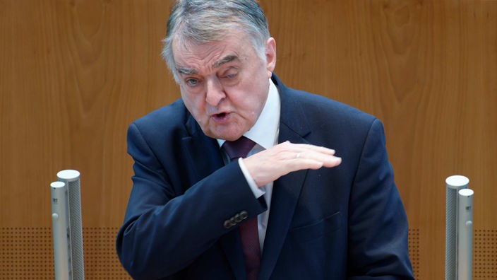 Ein Mann im dunkelblauen Anzug und schütterem grauen Haar redet gestikulierend am Rednerpult des NRW-Landtags.
