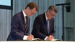 NRW-Ministerpräsident Hendrik Wüst (CDU) (links) bei der Unterzeichnung des Reviervertrags