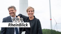 Bundeswirtschaftsminister Robert Habeck (Grüne) und NRW-Wirtschaftministerin Mona Neubaur (Grüne) posieren lachend zusammen vor Windrädern