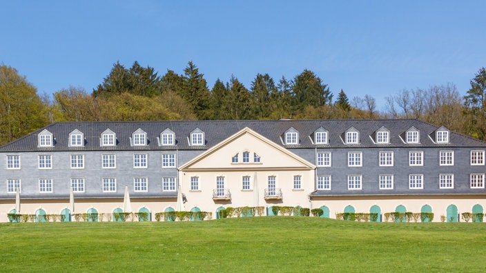 Schloss Haniel in Wermelskirchen steht frisch renoviert auf einem Hügel vor blauem Himmel