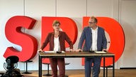 Sarah Pilipp und Jochen Ott in der Landeszentrale der NRW-SPD vor einem großen SPD-Logo