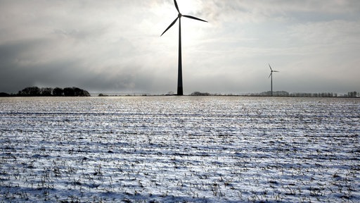 Zwei Windraeder drehen sich am Rande von schneebedeckten Feldern in Bottrop-Kirchhellen.