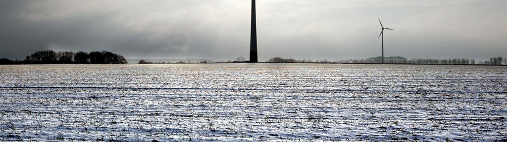 Zwei Windraeder drehen sich am Rande von schneebedeckten Feldern in Bottrop-Kirchhellen.