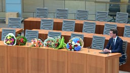 Ministerpräsident Hendrik Wüst auf der Regierungsbank, neben ihm liegen viele Blumensträuße