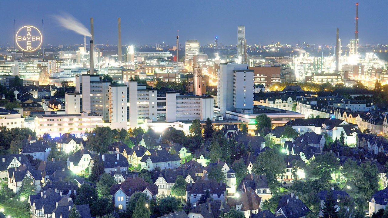 Der Chemie-Park des Bayer-Konzerns hinter der Kulisse der Leverkusener Innenstadt und der alten Werkssiedlung (vorne).  