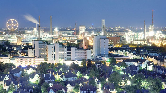 Der Chemie-Park des Bayer-Konzerns hinter der Kulisse der Leverkusener Innenstadt und der alten Werkssiedlung (vorne).  