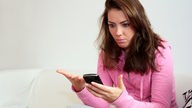 Eine Frau schaut entsetzt auf ihr Smartphone.