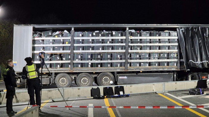 Einsatzkräfte der Polizei stehen vor einem Lastwagen auf der Autobahn 1 bei Hagen an der Unfallstelle.