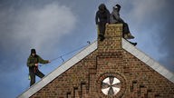 Drei Aktivisten:innen auf einem Dach in Lützerath
