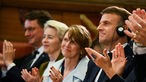 Nebeneinander sitzen Hendrik Wuest, die Präsidentin der Europäischen Kommission Ursula von der Leyen, die Frau des deutschen Bundespräsidenten Elke Buedenbender, der französische Präsident Emmanuel Macron und seine Frau Brigitte Macron.