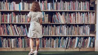 Ein Kind steht vor einem Bücherregal