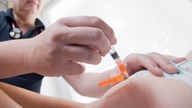  Ein Kinderarzt impft ein einjähriges Kind in den Oberschenkel mit dem Impfstoff Priorix