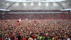 Leverkusener Fans feiern auf dem Stadionrasen nach Sieg gegen Werder Bremen