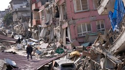 Türkei, Hatay: Ein Mann geht Anfang März über die Trümmer eingestürzter Gebäude in Hatay. Das Beben vor einem Monat in der Türkei und Syrien hat Zehntausende obdachlos gemacht und vertrieben