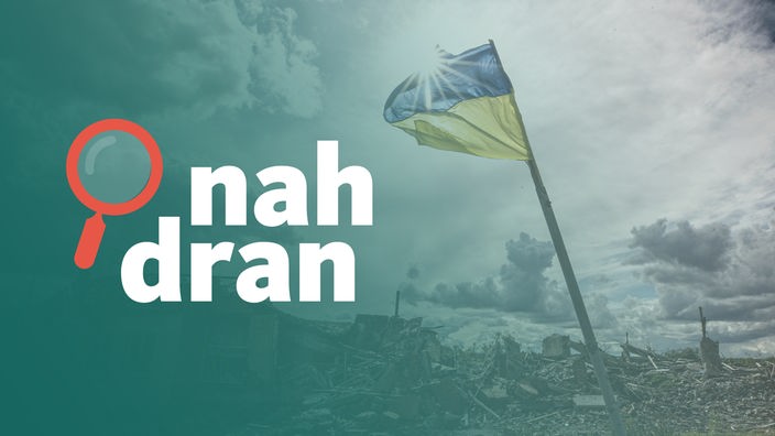 eine ukrainische Flagge weht vor einem zerstörten Gebäude im Wind