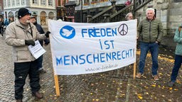 Demonstrierende mit einem Transparent "Frieden ist Menschenrecht" auf dem Marktplatz in Aachen