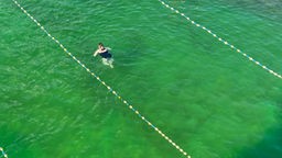 Eine Frau schwimmt im grünen Wasser