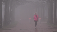 Eine Joggerin läuft durch dichten Nebel