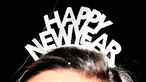 Eine Frau trägt zum Jahreswechsel einen Haarreif mit der Aufschrift "Happy New Year"